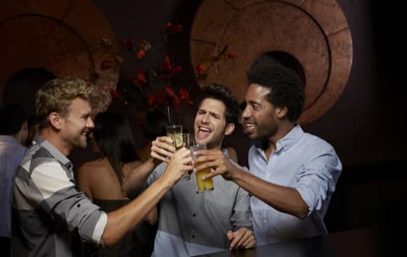 Friends toasting with drinks at a bar